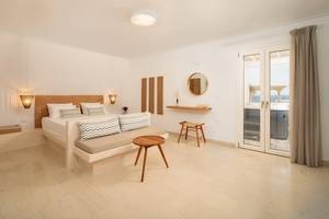 Ein modernes Schlafzimmer im Proteas Hotel mit einem Bett, Nachttischen und einem Blick auf das Meer.
