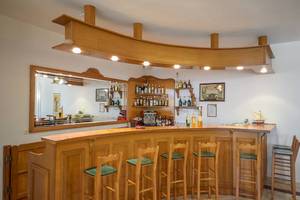 Rezeption und Bar im Proteas Hotel & Suites mit hölzerner Einrichtung und grünen Stühlen.