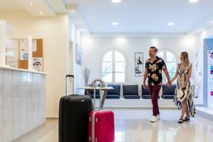 Ein Paar geht im Eingangsbereich des Mikri Vigla Hotels mit Gepäck