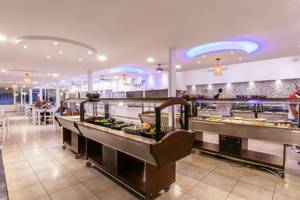 Buffet im Restaurant des Mikri Vigla Hotels mit verschiedenen Speisen und Gästen, die sitzen.