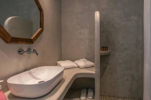 Badezimmer im Mikri Vigla Hotel mit Waschbecken, Spiegel und Dusche.