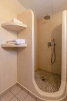 Dusche im Mikri Vigla Hotel mit zwei Regalen und Handtüchern.