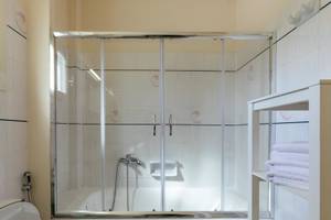 Badezimmer im Mikri Vigla Hotel mit Glasdusche und Badewanne