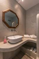 Das Badezimmer im Mikri Vigla Hotel mit einer Badewanne, Waschbecken und Handtüchern.