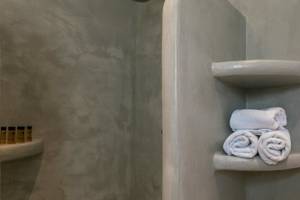 Dusche im Mikri Vigla Hotel mit weißen Handtüchern und Hygieneprodukten.