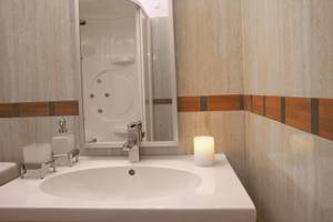 Badezimmer im Lagos Mare Hotel mit weißem Waschbecken und Spiegel.