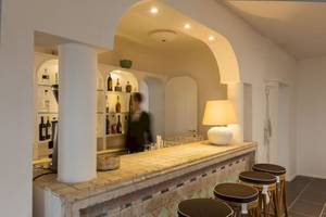 Innenansicht der Bar im Mare Pineta Hotel mit Theke, Stühlen und Lampen.
