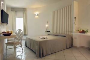 Hotelzimmer im Mare Pineta Hotel mit Bett, Tisch, Fernseher und Obstkorb.