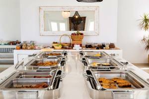 Frühstücksbuffet im Paros Agnanti Resort & Spa mit verschiedenen Speisen in Edelstahlschalen.