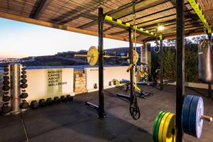 Fitnessbereich im Paros Agnanti Resort & Spa mit verschiedenen Geräten und einer Wand mit Zitat.