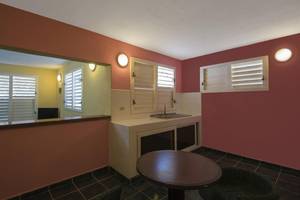 Kleine Küche im Zimmer des Gran Caribe Villa Tortuga Hotels mit Tisch, Stühlen und Fenstern.