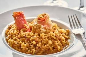 Ein Teller mit Reisgericht mit Krabben und Speck auf einem weißen Teller mit Gabel