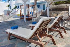Lounge-Stühle und Hängematten im Pyrgaki Hotel mit Blick auf ein weißes Gebäude.