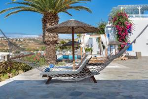 Loungebereich im Pyrgaki Hotel mit Palme und Hängematte vor einem Swimmingpool