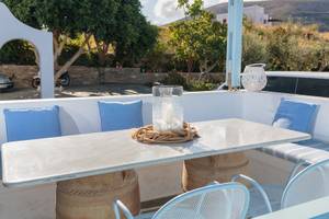 Außenansicht der Terrasse des Pyrgaki Hotels mit Tisch, Stühlen und Kissen.
