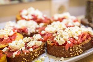 Mehrere Scheiben Brot mit Feta-Käse und Tomaten auf einem Tablett im Pyrgaki Hotel.