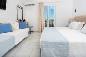 Schlafzimmer im Pyrgaki Hotel mit Balkon, zwei Betten, Klimaanlage und Fernseher.