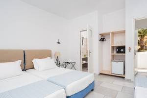 Doppelzimmer im Pyrgaki Hotel mit zwei Betten, weißen Wänden und blauen Laken.