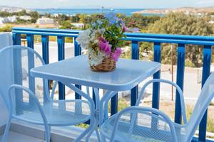 Ein Balkon mit Blumen auf einem Tisch und zwei Sesseln im Pyrgaki Hotel.