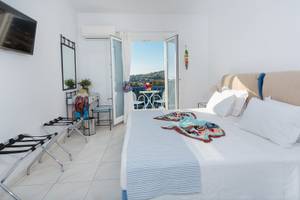 Schlafzimmer im Pyrgaki Hotel mit Blick auf einen Balkon und eine Terrasse.