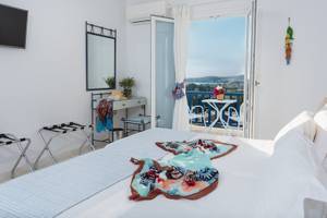 Schlafzimmer mit Balkon im Pyrgaki Hotel, mit Bett, Klimaanlage, Fernseher und Blick auf die Landschaft.