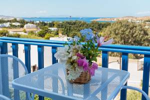 Balkon mit blauem Geländer und Blick auf das Meer, Blumen in einem Korb auf einem Tisch