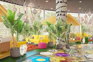 Innenraum des nhow Amsterdam RAI mit gelben Sofas, bunten Teppichen und vielen Pflanzen.