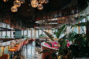 Innenansicht des Restaurants im nhow Amsterdam RAI mit hängenden Pflanzen und modernen Möbeln.