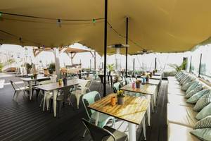 Terrasse des Leonardo Hotel Amsterdam Rembrandtpark mit Tischen und Stühlen unter einem Zeltdach.