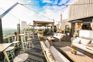 Dachterrasse des Leonardo Hotel Amsterdam Rembrandtpark mit Tischen und Stühlen.