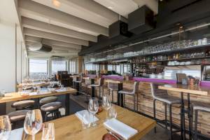 Innenansicht des Restaurants im Leonardo Hotel Amsterdam Rembrandtpark mit Tischen, Stühlen und einer Bar.