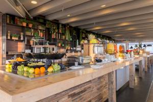 Frühstücksbuffet im Leonardo Hotel Amsterdam Rembrandtpark mit Obst, Säften und anderen Speisen.