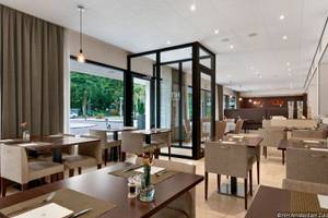 Restaurant des NH Amsterdam Zuid Hotels mit Tischen und Stühlen, Blick auf die Straße