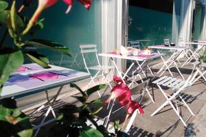 Terrasse des Ripa Roma Hotels mit mehreren weißen Tischen und Stühlen draußen.