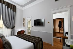 Schlafzimmer im Bettoja Hotel Massimo d'Azeglio mit einem Bett, Fernseher und Kleiderschrank.