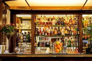 Die Bar im Bettoja Hotel Massimo d'Azeglio mit vollbestückten Regalen, Gläsern, Früchten und Pflanzen.