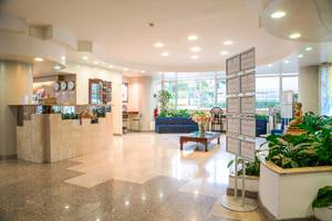 Empfangsbereich des Pineta Palace Hotels mit Rezeptionstresen, Sofas, Pflanzen und Dekor.