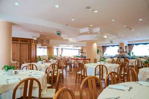 Innenansicht des Restaurants im Pineta Palace Hotel mit gedeckten Tischen und Stühlen.