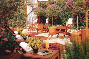Terrasse des Dei Mellini Hotels mit Holzliegen, Pflanzen und einem Glas Orangensaft