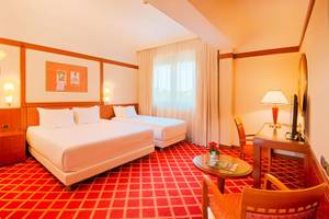 Doppelzimmer im NH Roma Villa Carpegna Hotel mit zwei Betten, Tisch, Stühlen und Dekor.