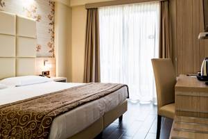 Hotelzimmer im Pineta Palace mit Bett, Schreibtisch und Fenstern.