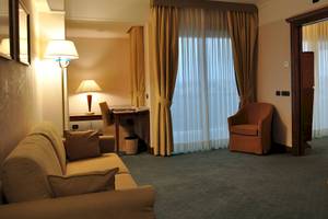 Innenansicht eines Hotelzimmers im Pineta Palace mit Sofa, Schreibtisch, Stühlen und Fenstern.