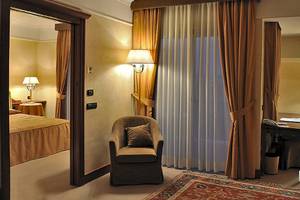 Hotelzimmer im Pineta Palace mit Bett, Stuhl, Schreibtisch und Lampen.