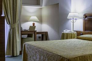 Schlafzimmer im Pineta Palace Hotel mit Bett, Schreibtisch und Lampen.