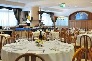 Speisesaal im Pineta Palace Hotel mit gedeckten Tischen, Flaschen und Gläsern.
