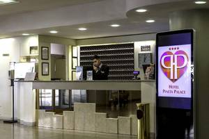 Hotelrezeption mit digitalem Schild und Mitarbeiter, der telefoniert.