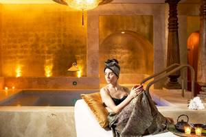 Eine Frau sitzt im Liegestuhl im Spa-Bereich des Metropole Hotels, neben einem Whirlpool.