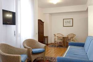 Wohnzimmer im San Marco Palace Hotel mit Fernseher, Korbstühlen und Tisch.