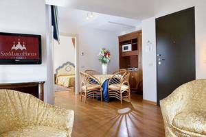 Innenraum des San Marco Palace Hotels mit Wohnzimmer, Esstisch, Fernseher und Schlafzimmer.