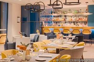 Innenbereich des Avani Rio Novo Hotels mit gelben Stühlen, Tischen und einer Bar.